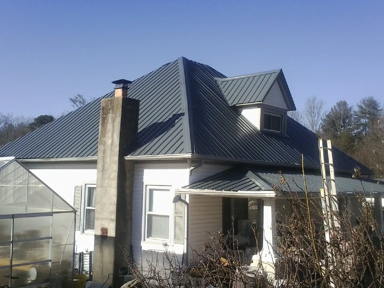 Dark blue standing seam metal roof on a white farmhouse with dormer — Slate & Tile Roof Repair by Roofing Brothers in Alcolu