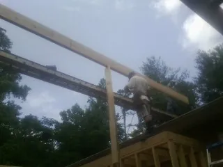 Carpenter setting a ridge beam over a new addition frame — Ice Dam Removal by Roofing Brothers in Alcolu