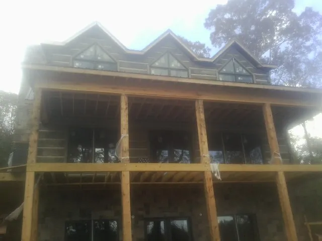 Dormers and porch framing on a large log home under construction — Roof Coating work by our crew in Alcolu