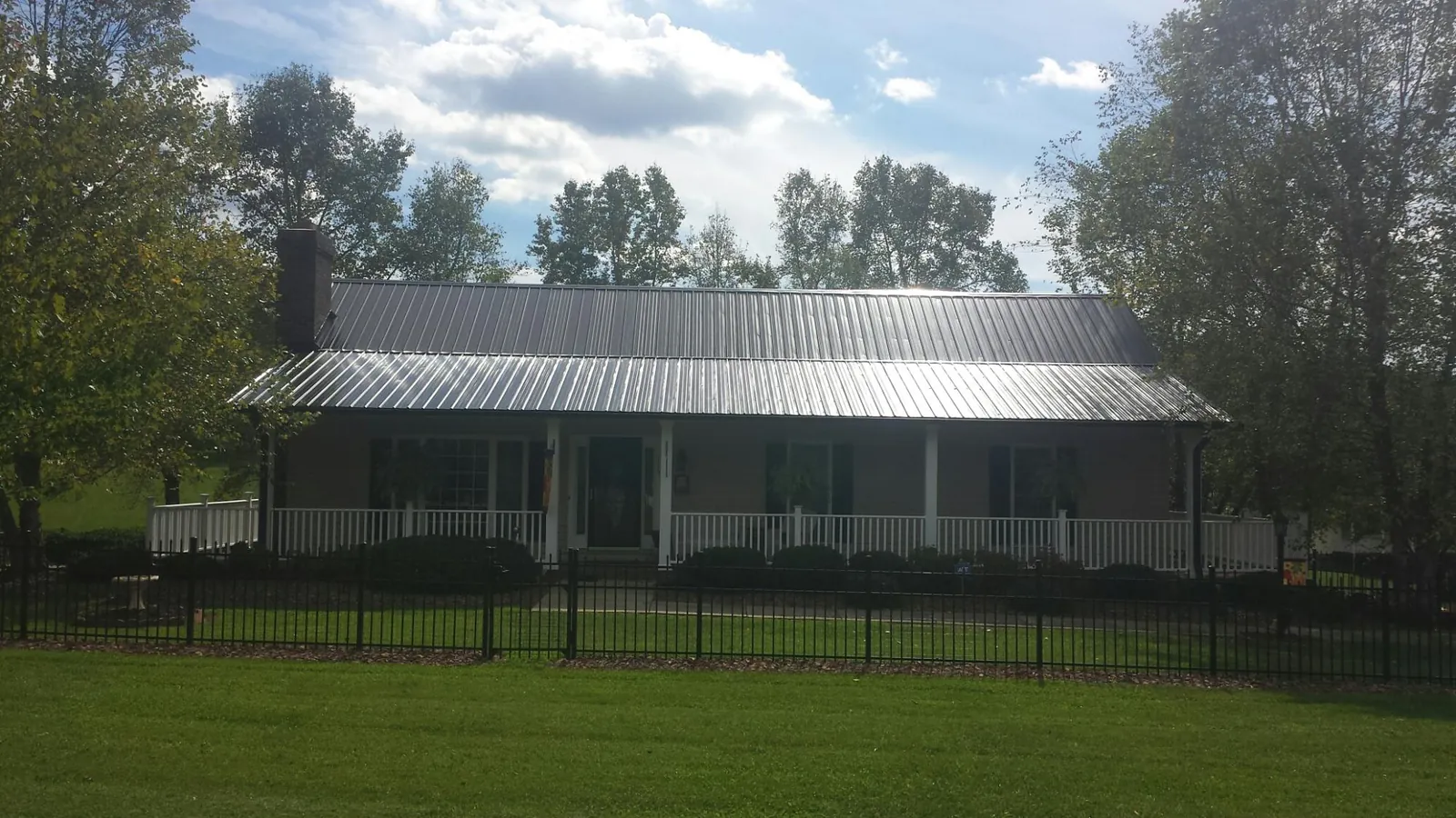 Gray metal roof on a brick ranch with a full width front porch — Gutter Guard Installation work by our crew in Alcolu