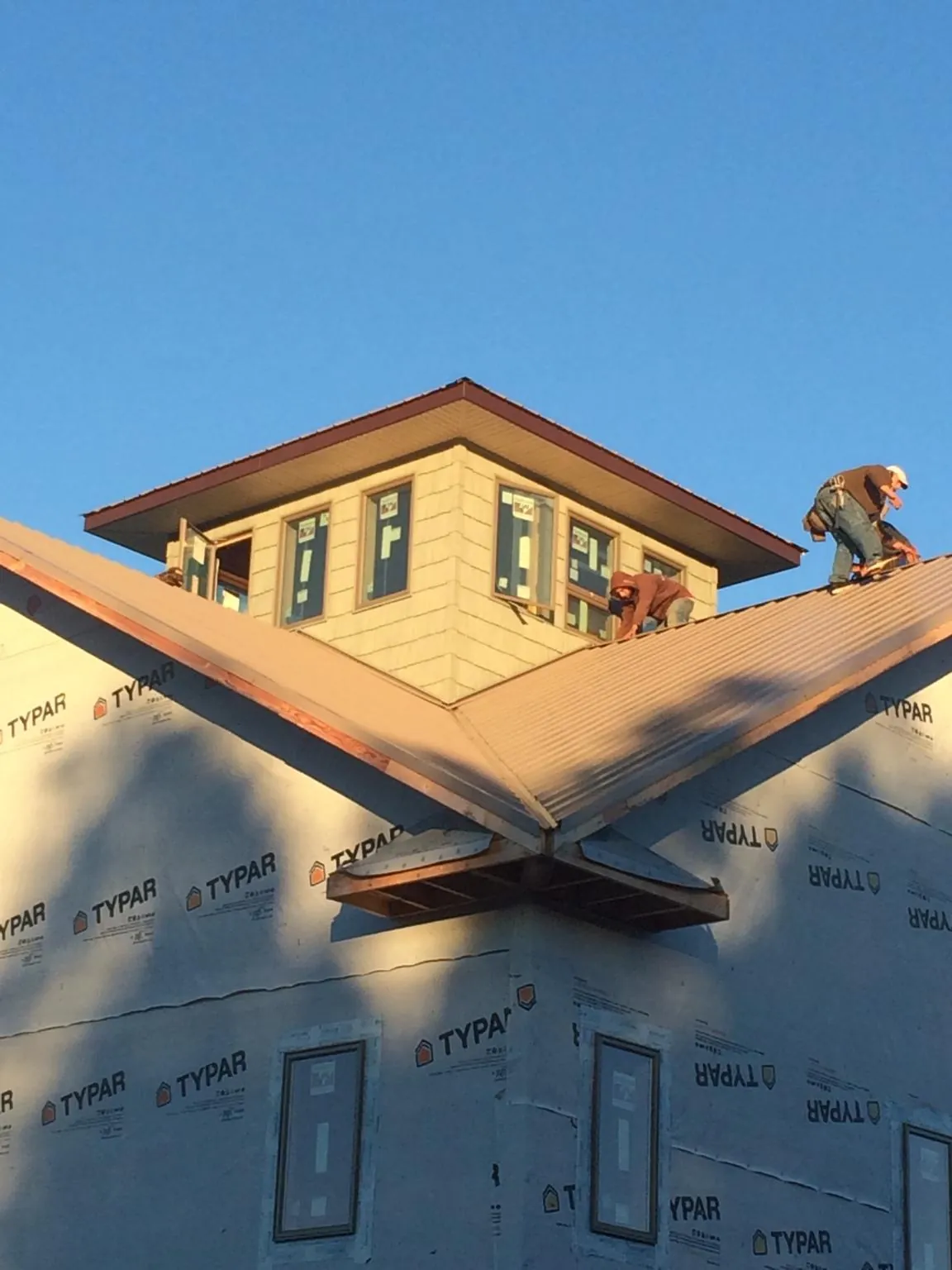 Roofers working around a rooftop cupola on a new metal roof at sunset — Roof Waterproofing in Alcolu by Roofing Brothers